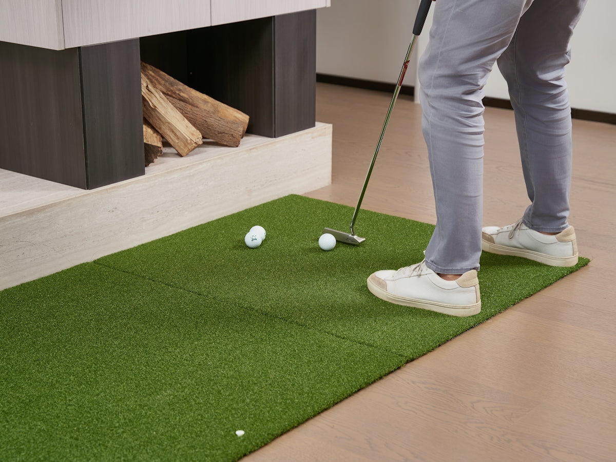 Man practicing golf putting indoors on indoor green mat